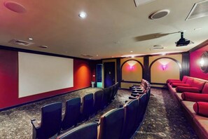 Une salle de cinéma avec des rangées de sièges, un écran et un système de projection.