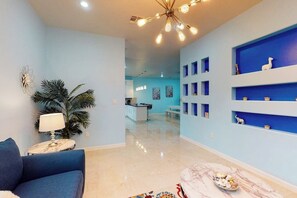 A modern living room with a blue sofa, a white lamp, and a decorative plant. - Blue Dolphin Beach House (South Padre Island)