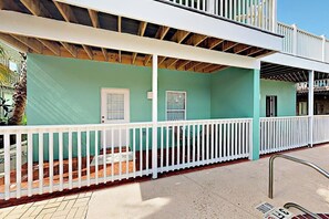 A two-story building with a white balcony railing, a covered patio area, and a visible door. - Marlin Street C - Pool, 2 Minutes from the Beach (South Padre Island)