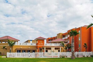 A hotel with multiple buildings, a white fence, and palm trees. - La Isla Condominiums #C105 (South Padre Island)