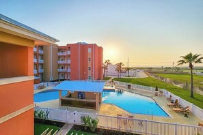 A hotel with a swimming pool, outdoor seating, and a view of the sunset. - La Isla Condominiums #C105 (South Padre Island)