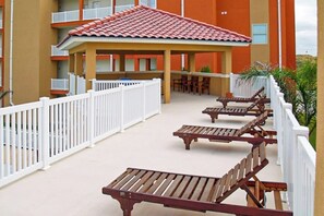 A covered outdoor seating area with wooden benches and a white fence. - La Isla Condominiums #C105 (South Padre Island)