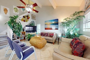 A living room with a sofa, armchairs, a coffee table, a TV, and a ceiling fan. - White Granite at 106 East Huisache (South Padre Island)
