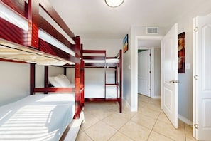 A room with bunk beds, a door, and a hallway. - White Granite at 106 East Huisache (South Padre Island)