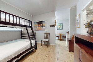 Quarto compacto com beliche, uma mesinha, uma cadeira e um armário.