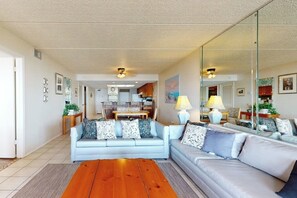 Ein Wohnzimmer mit einer Couch, einem Couchtisch und einem Essbereich im Hintergrund.