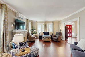 A living room with a fireplace, sofas, a coffee table, and a TV. - Salty Toes - Fenced Yard, Steps to the Sand (Galveston)