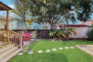 A backyard with a wooden deck, a covered patio, and a grassy lawn. - Salty Toes - Fenced Yard, Steps to the Sand (Galveston)