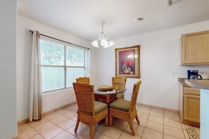 A dining area with a round table and four chairs, a window with blinds, a ceiling light fixture, and a framed picture on the wall. - 9 Augusta Casita at SPI Golf Course (Laguna Vista)
