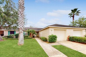 A single-story house with a garage, a well-maintained lawn, and a palm tree. - 9 Augusta Casita at SPI Golf Course (Laguna Vista)