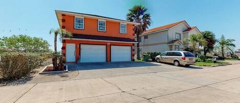 A two-story house with a garage, a driveway, and a parked car.