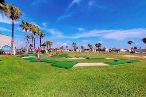 A miniature golf course with green fairways, sand traps, and a clear blue sky. - Long Island Village 790 W Oyster Drive Bungalow (Port Isabel)