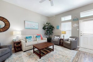 Ein Wohnzimmer mit einer Couch, Sesseln, einem Couchtisch und einer Pflanze.