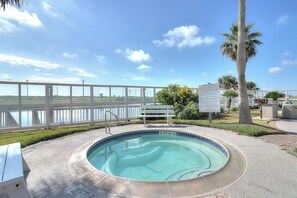 A swimming pool with a view of the water, a white fence, and a sign. - Beach Club - Casa Del Sol (Corpus Christi)