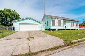 A two-story house with a garage and a small front yard. - Sea Glass Cottage - Dog-Friendly, Near the Beach (Galveston)