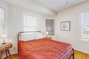 A bedroom with a bed, a nightstand, a lamp, and a framed picture on the wall. - Sea Glass Cottage - Dog-Friendly, Near the Beach (Galveston)