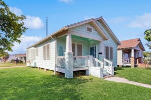 A single-story house with a front porch, a staircase leading to the entrance, and a clear sky. - Sea Glass Cottage - Dog-Friendly, Near the Beach (Galveston)