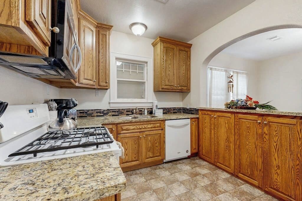 A kitchen with wooden cabinets, a gas stove, and a dishwasher.