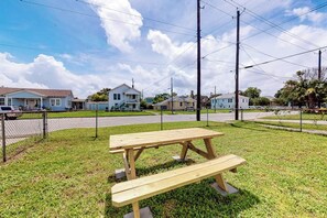 A picnic table in a grassy area with houses in the background. - Sea Glass Cottage - Dog-Friendly, Near the Beach (Galveston)