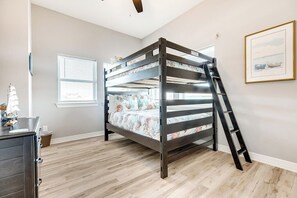 A bunk bed in a room with wooden flooring, a window with blinds, and a ladder. - Seahorse Beach House (Galveston)