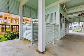 A covered outdoor area with a concrete floor, metal railings, and a view of a building under construction. - Pointe West - Bay Breeze Paradise (Galveston)