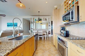 Eine moderne Küche mit Granit Arbeitsplatten, Edelstahlgeräten und einem Essbereich mit einem weißen Tisch und Stühlen.