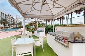 Eine Außenpatio mit Grill, Sitzgelegenheit und Pool im Hintergrund.