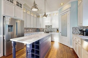 A modern kitchen with white cabinets, a marble countertop, and stainless steel appliances. - Blue Claws - Bayfront, Elevator & Resort Pools (Galveston)