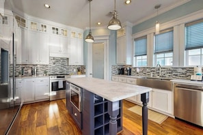 A modern kitchen with white cabinets, a marble island, and stainless steel appliances. - Blue Claws - Bayfront, Elevator & Resort Pools (Galveston)