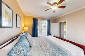 Ein Hotelzimmer mit einem Bett, einem Deckenventilator, einem Fenster mit Vorhängen und einer Tür.