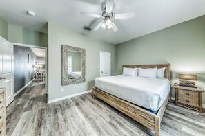 Een slaapkamer met een groot bed, een plafondventilator en een houten vloer.