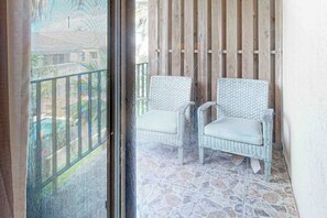 Ein Balkon mit zwei Korbstühlen und einem Steinplattenboden.