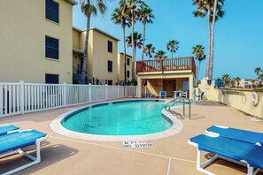 A pool area with lounge chairs, a no-diving sign, and a building with a balcony. - Aztec Habitat No 19 - Pool, 1 Minute to the Beach (South Padre Island)