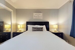 A neatly made bed with a pillow that reads 'Families are Forever' and a sign above stating 'Welcome to our Beach House.' - Inverness #304 - Steps to Beach, Pool & Hot Tub (South Padre Island)