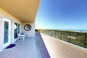 A balcony with a view of the ocean, a door with a glass panel, and a circular window. - Suntide II Condominiums #106 (South Padre Island)