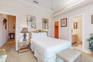 A bedroom with a large bed, bedside tables, a lamp, and artwork on the walls. - Casa Emilio II Condominiums 201C (South Padre Island)
