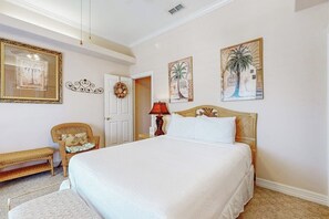 Une chambre avec un grand lit, une chaise, une lampe et des œuvres d’art murales.