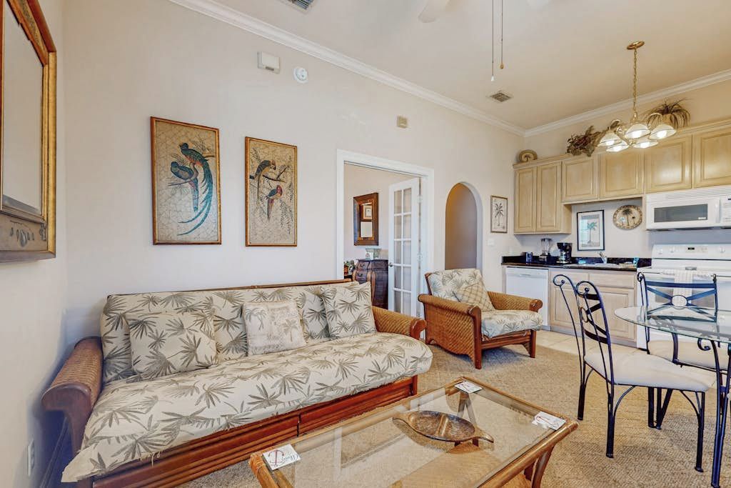 A living room with a sofa, chairs, a glass coffee table, and artwork on the walls.