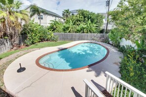 A swimming pool with a brick edge, surrounded by a wooden fence and lush greenery. - Aries Chateau - Private Pool, Half Block to Beach (South Padre Island)