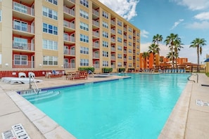 A hotel with a swimming pool, multiple balconies, and palm trees. - Gulfview I #207 - Bay Views, Pool, Walk to Beach (South Padre Island)