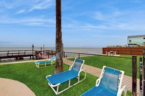 A beachside area with a wooden deck, a fence, and blue lounge chairs. - Marlin Arms Condominiums #10 (South Padre Island)