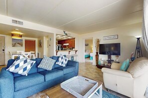 A living room with a blue sofa, a beige armchair, and a television. - Marlin Arms Condominiums #10 (South Padre Island)
