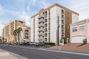 A multi-story hotel with balconies, a parking lot, and a clear sky. - Florence Condominiums #707 (South Padre Island)