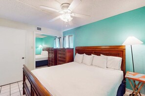 A bedroom with a wooden bed, a ceiling fan, a nightstand, and a lamp. - Florence Condominiums #707 (South Padre Island)