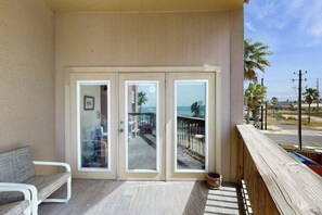 Een balkon met uitzicht op het strand en een houten leuning.