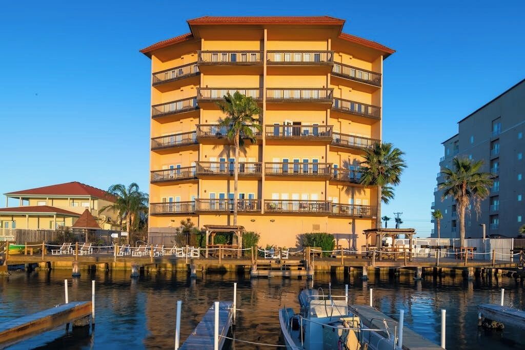 A multi-story hotel with balconies, a dock, and a marina.
