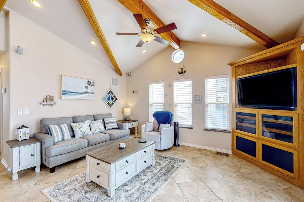 A living room with a ceiling fan, a sofa set, a coffee table, a TV, and a fireplace.