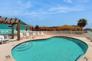 Una piscina con sillones de descanso y una pérgola.