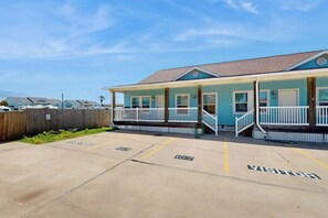 A building with a porch and a parking area with marked spaces. - Flip Flop and Relax - Year-Round Pool, Near Beach (Port Aransas)