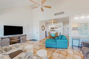 A living room with a television, a ceiling fan, and a dining area with chairs and a table. - Puente Vista - Aloha, Sunset on the Bay (Corpus Christi)